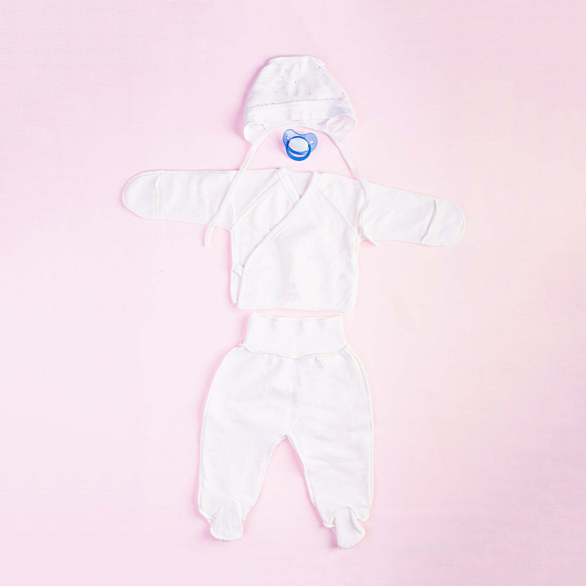 Baby clothes and other stuff for child on pink background. Newborn baby concept. Top view